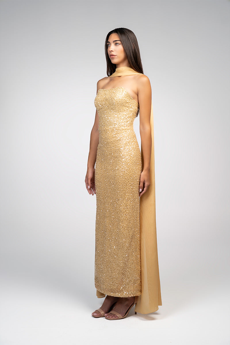 Gold embroidered gown by Joanna Andraos featuring intricate embroidery and elegant design, displayed on a dress form.