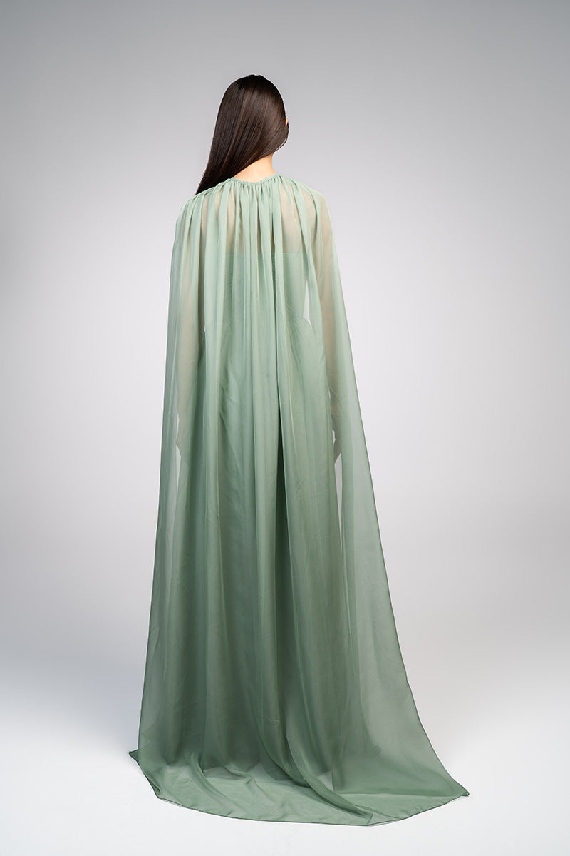 Elegant strapless gown by Joanna Andraos featuring a detachable cape, shown in a sophisticated pose on a neutral background.