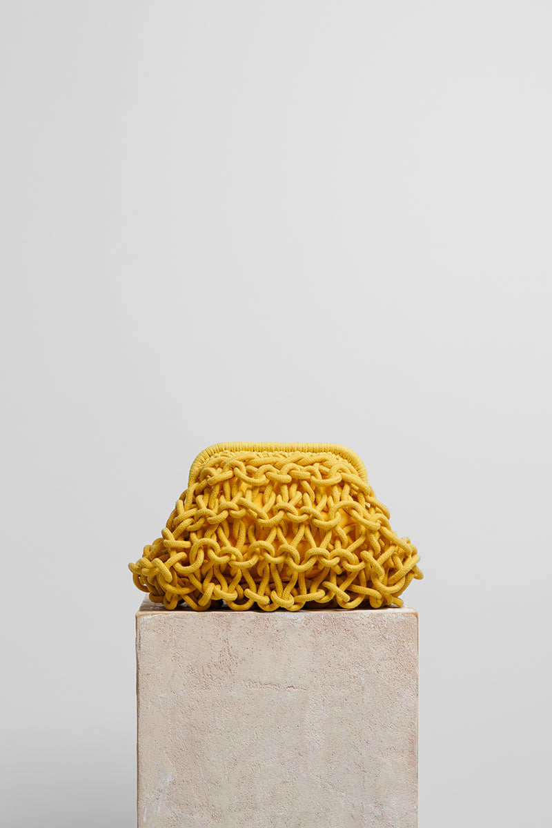 Yellow small rope clutch bag by Folklore The Label featuring a compact design and rope strap for versatile style.