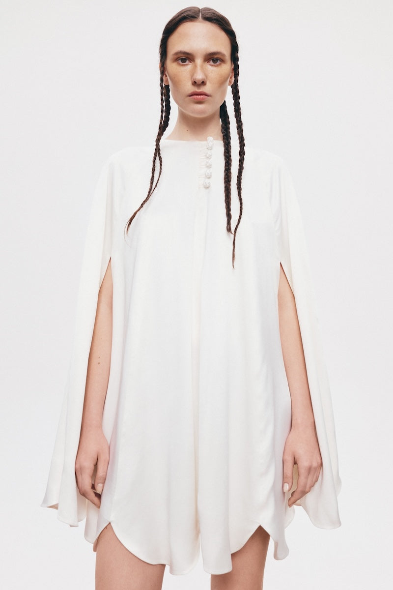 White GUL cape coat by PODYH, featuring a stylish design with a hood and elegant fit, perfect for layered winter fashion.
