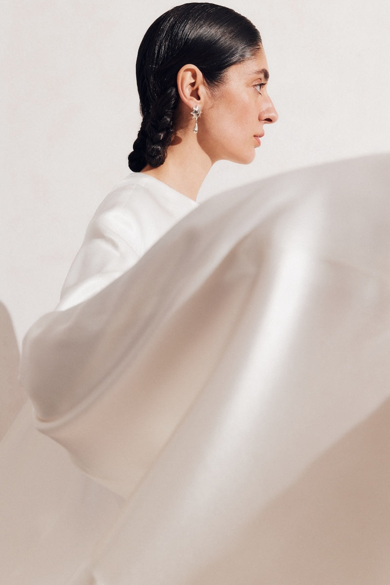 PODYH white GUL cape coat displayed on a hanger, showcasing its elegant design and lightweight fabric.