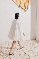 White PODYH GUL cape coat shown hanging on a rack with a minimalist background.