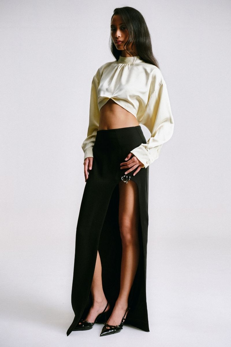 Black maxi skirt with cut-out slit and piercing detail by Sean Sheila, shown from a side view.