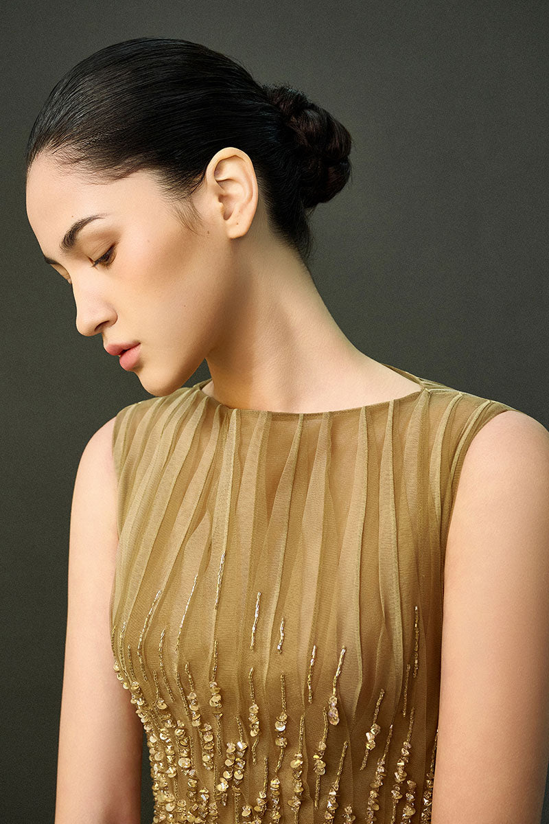 Light brown Noura gown by EEGEN Studio, elegant full-length dress with flowing fabric and detailed design.