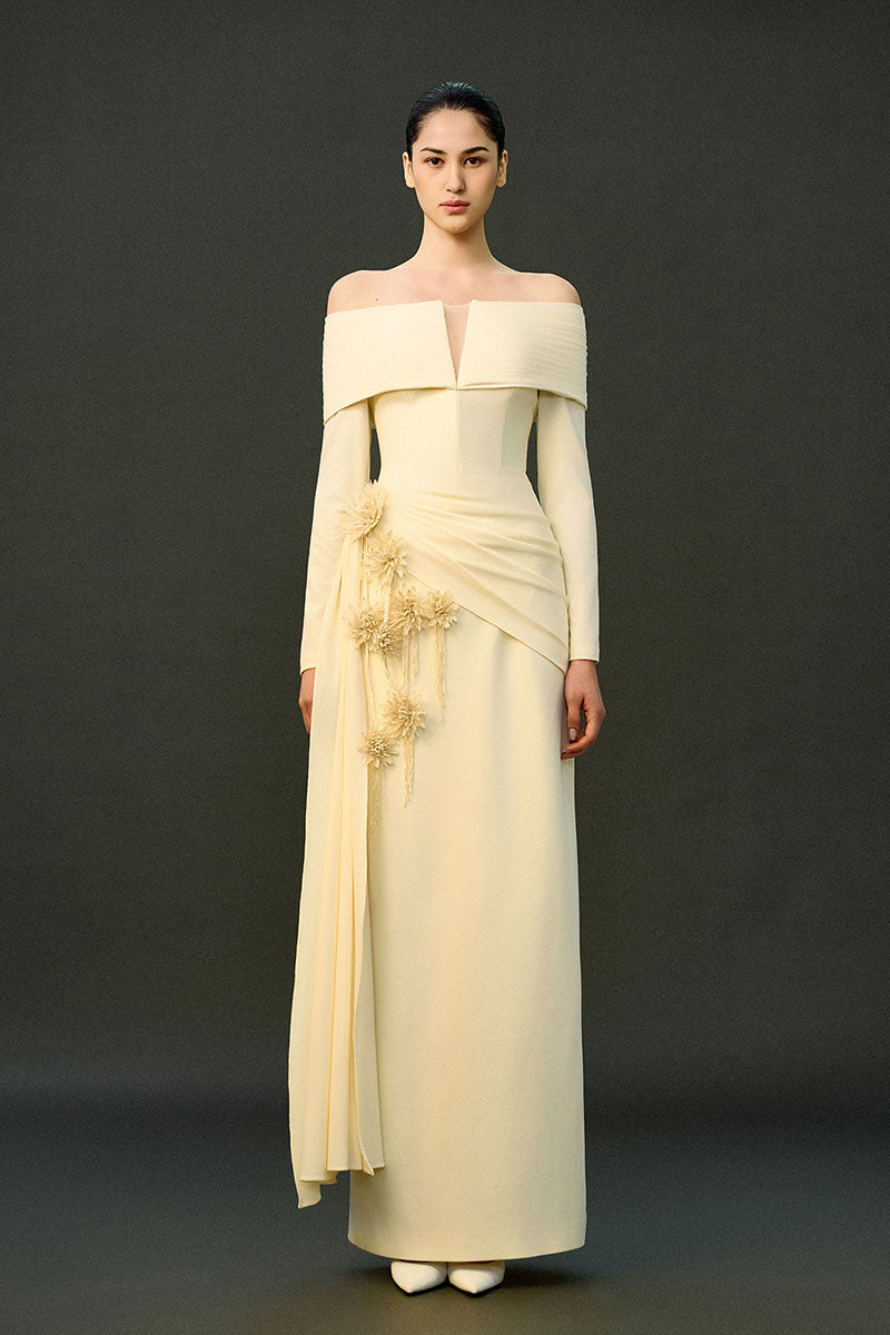 Off-white Amira gown by EEGEN Studio featuring elegant flowing fabric and detailed embroidery, displayed on a dress form.