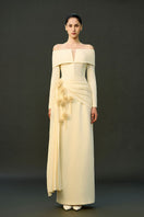 Off-white Amira gown by EEGEN Studio featuring elegant flowing fabric and detailed embroidery, displayed on a dress form.