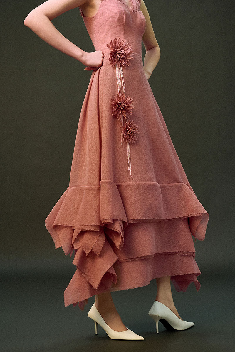 Pink DUNE gown by EEGEN STUDIO with flowing fabric and elegant design, shown hanging on a wooden hanger.