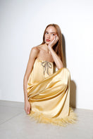 Butter yellow satin gown with a bow detail, designed by Rayane Bacha, featuring elegant flowing fabric and a sophisticated look.