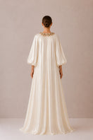 Nihan Peker Sedef dress in vanilla, elegant gown with flowing fabric and detailed design, shown on a model.