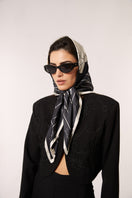 Black Señorita Luisa scarf displayed draped over a neutral background, showcasing its soft fabric and elegant design.