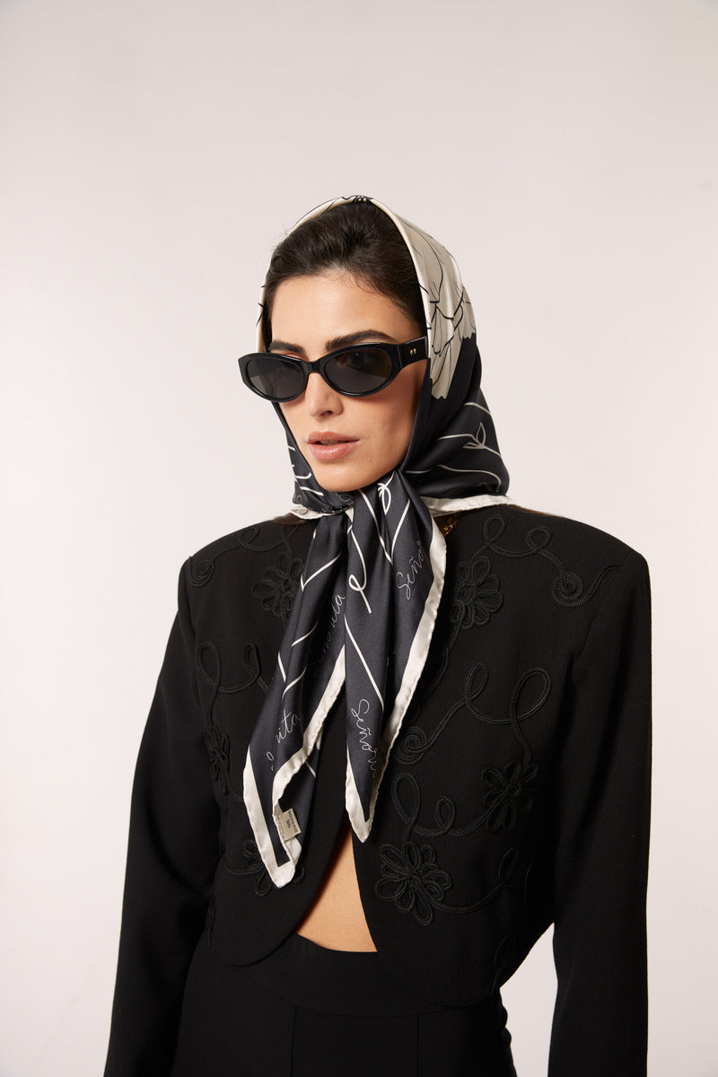 Black Señorita Luisa scarf displayed draped over a neutral background, showcasing its soft fabric and elegant design.