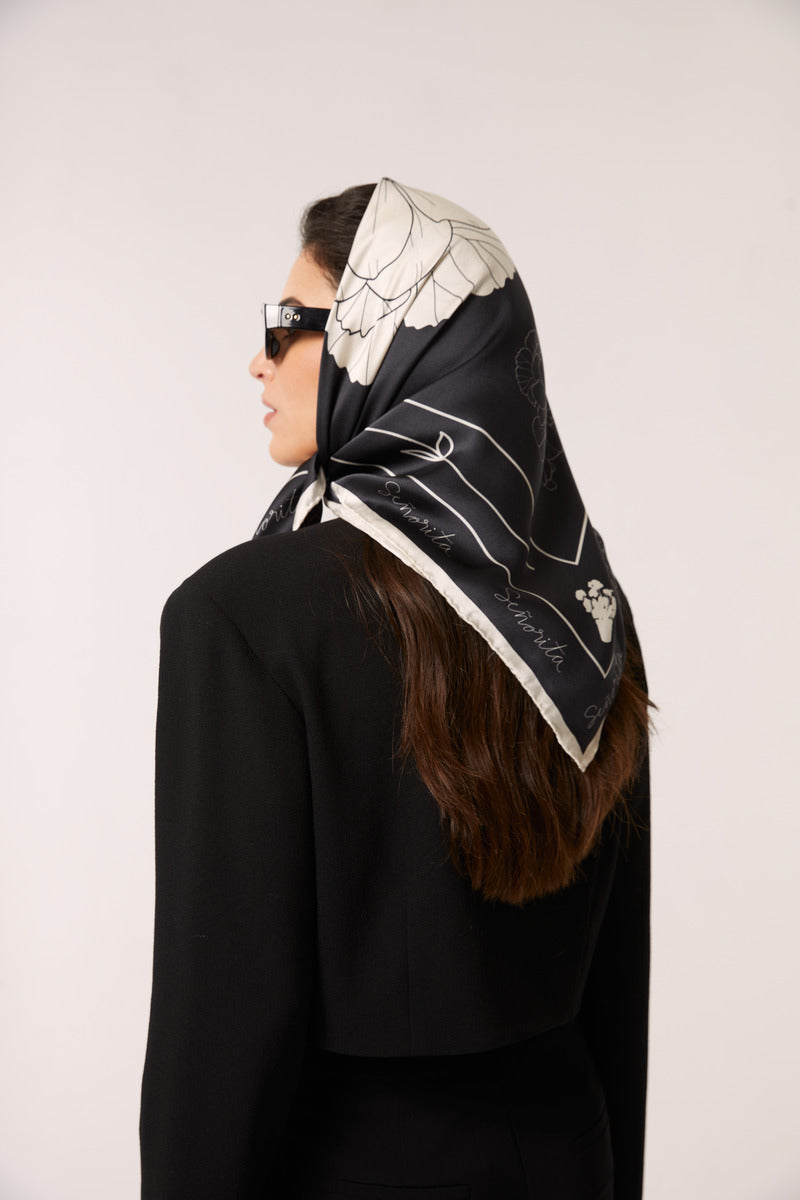 Black Señorita Luisa scarf draped over a neutral background, showcasing its soft fabric and elegant design.
