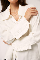 White Antonia blouse by Señorita, a stylish shirt with a relaxed fit, displayed on a hanger against a neutral background.