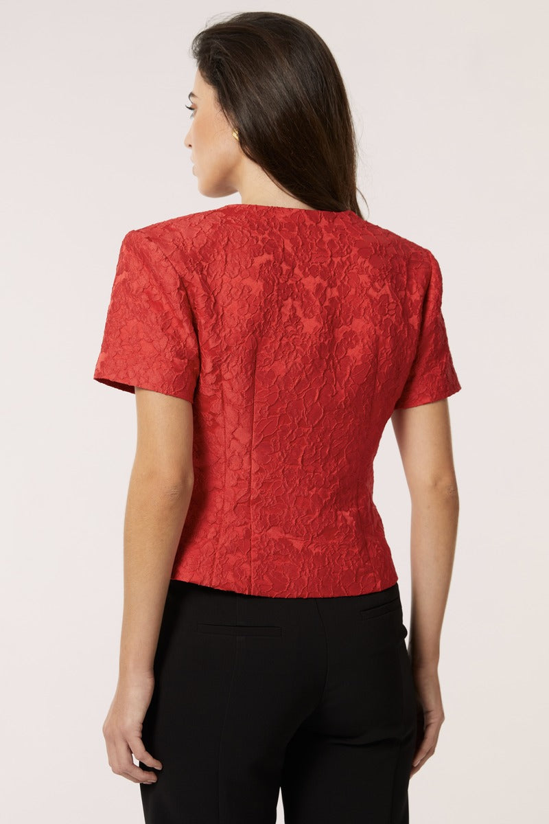 Red Señorita Aurora top, stylish women's blouse with a flattering fit, shown on a model in a fashion photoshoot.