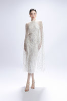White sequin midi cape dress by Valenciani, showcasing elegant draping and shimmering embellishments for formal occasions.