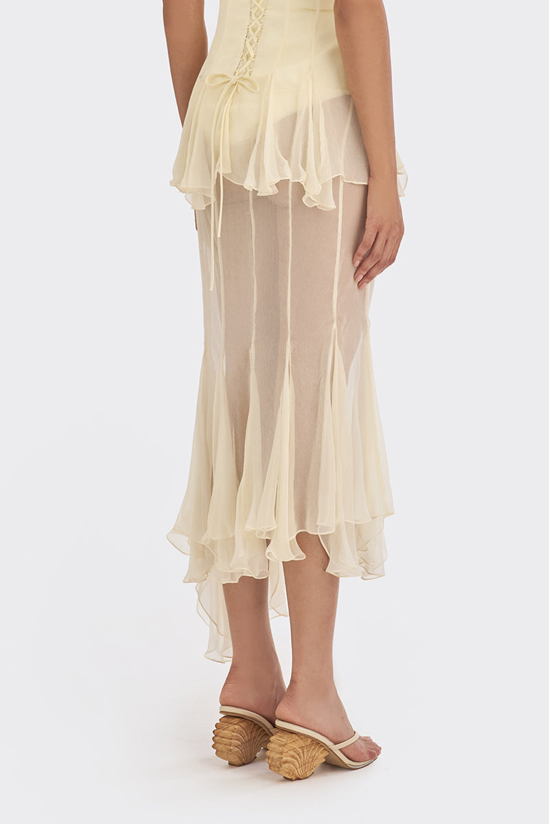 Light yellow asymmetric sheer maxi skirt from Stolen Stores featuring shell-shaped details and flowing, lightweight fabric.