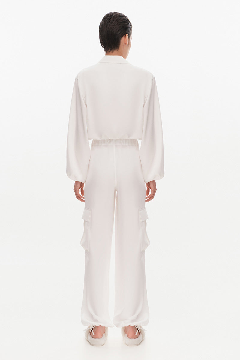 White Kris Marán silky bomber jacket shown from the back, featuring smooth fabric and stylish collar details.