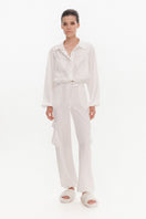 White silky cargo pants by KRIS MARÁN featuring a relaxed fit and multiple pockets, styled with a casual, modern look.