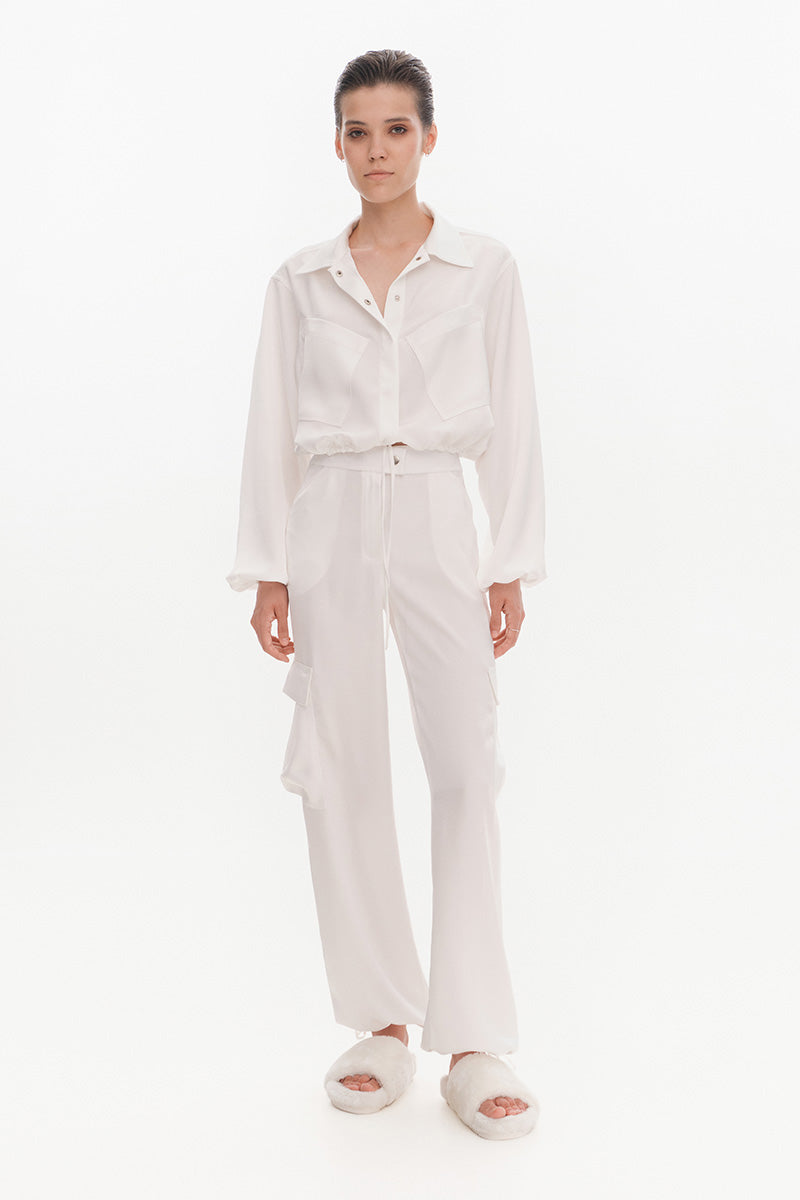 White silky cargo pants by KRIS MARÁN featuring a relaxed fit and multiple pockets, styled with a casual, modern look.