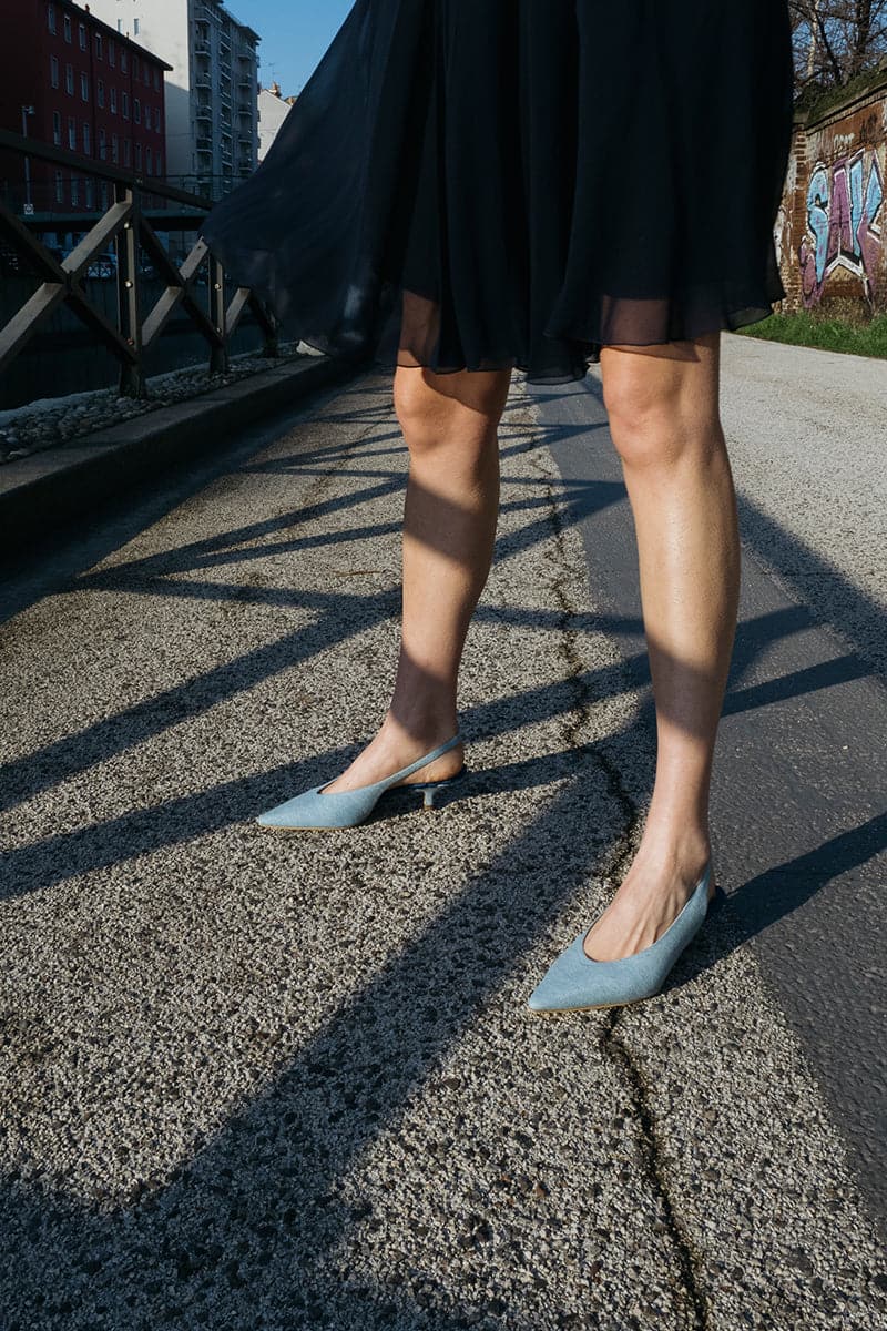 A pair of AERA Silvana blue denim slingback pumps with pointed heels and stylish design, shown from the front angle.