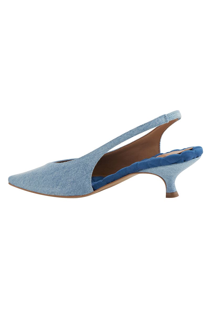 A pair of blue denim AERA Silvana slingback pumps with pointed heels, shown from the back view.