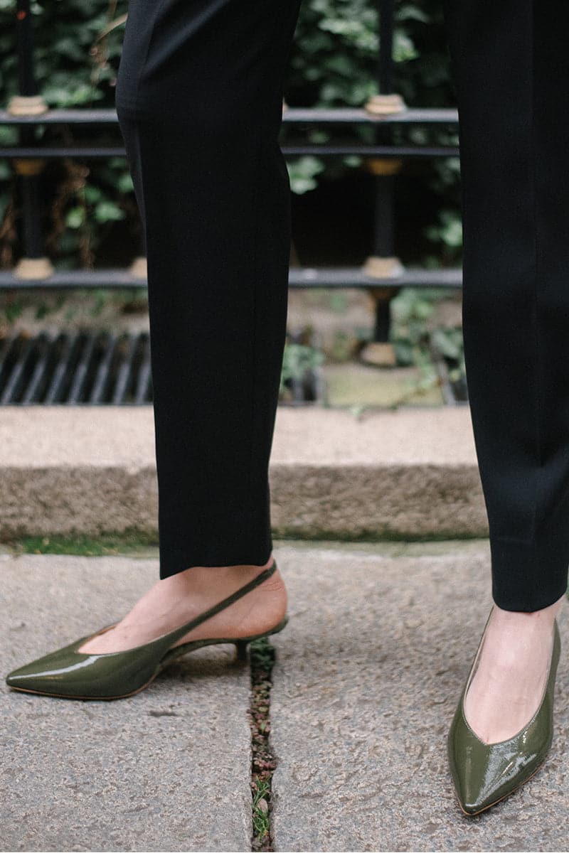 Green patent-effect slingback pumps by AERA featuring pointed heels and sleek design, shown in a stylish side view.
