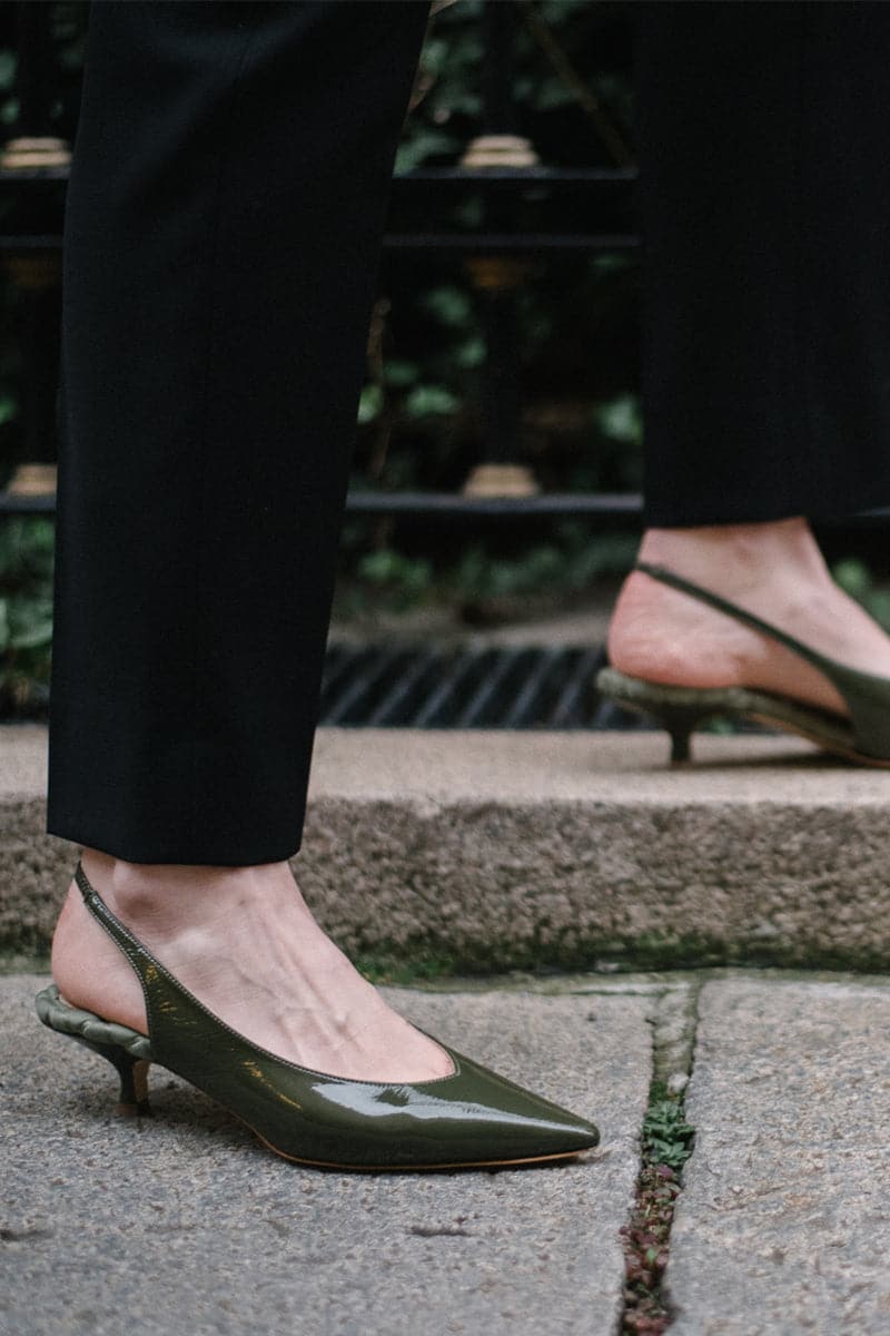 Green patent-effect slingback pumps by AERA, featuring pointed heels and elegant design, perfect for stylish outfits.