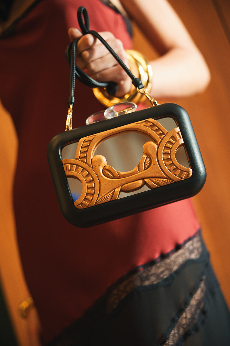 Black Sy&Vie clutch with sleek, curved mirror design, featuring a compact and stylish appearance perfect for evening accessories.