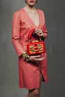 Sy&Vie Simetrís Isometra red clutch bag with sleek design, featuring a compact shape and textured finish.