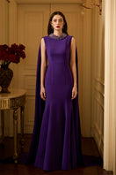 Sleeveless TIANA Crepe Cape Gown by I.H.F featuring a mermaid silhouette and a long back train on a model.