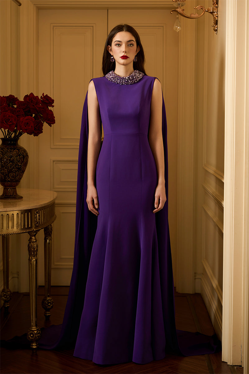 Sleeveless TIANA Crepe Cape Gown by I.H.F featuring a mermaid silhouette and a long back train on a model.