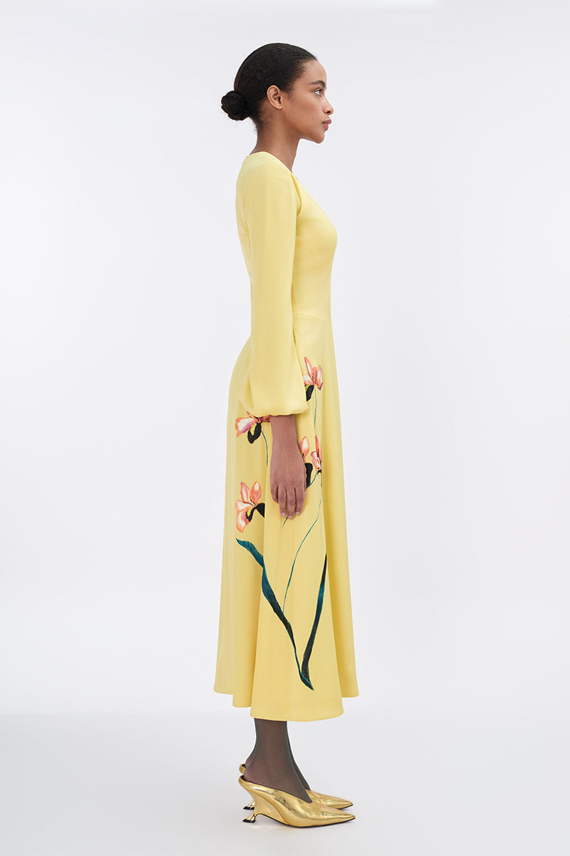 Soft yellow bishop sleeve flared midi dress by Tiny Ink, featuring flowing fabric and elegant design, displayed on a hanger.