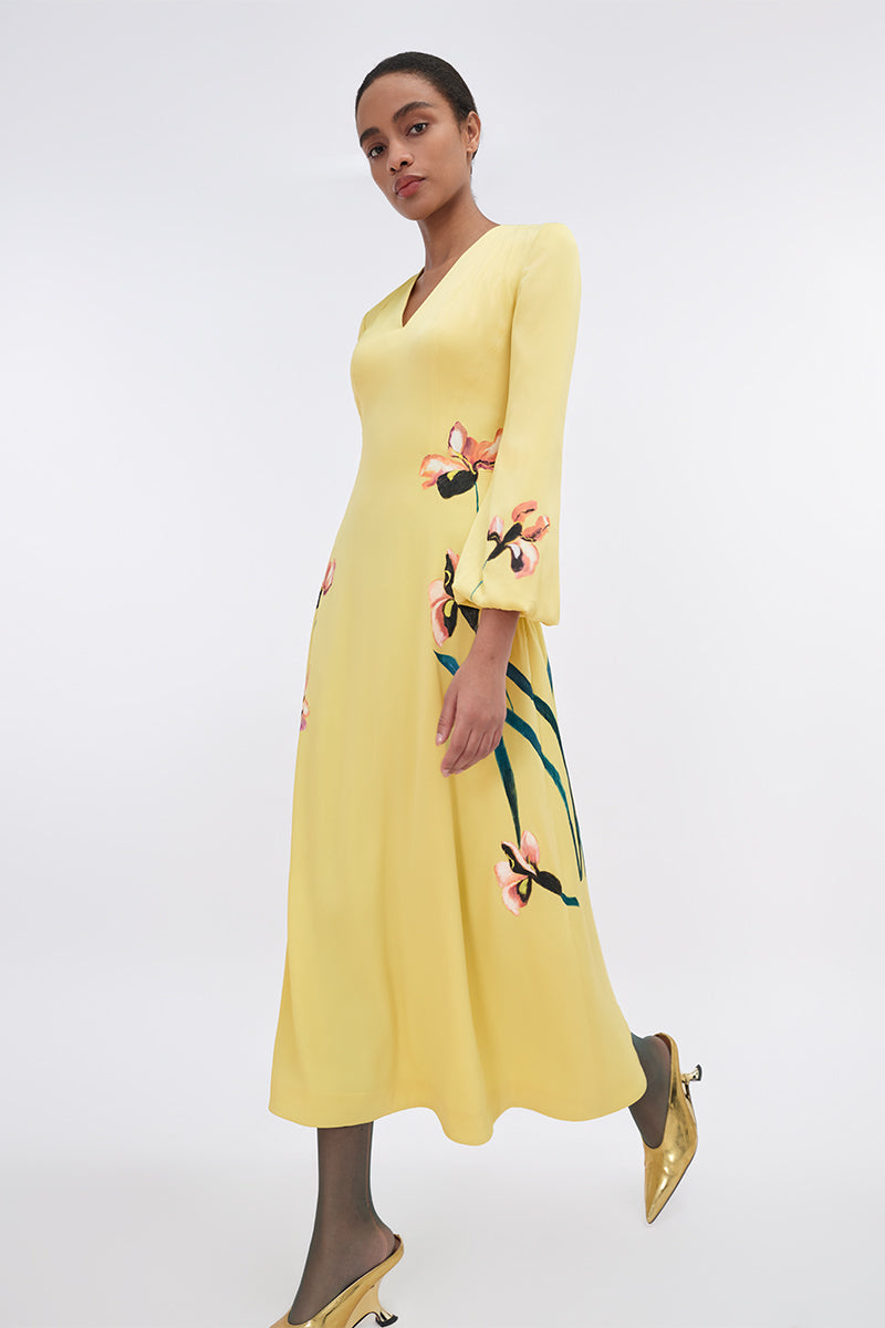 Soft yellow bishop sleeve flared midi dress by Tiny Ink, featuring flowy fabric and elegant design, shown hanging on a model.