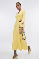 Soft yellow bishop sleeve flared midi dress by Tiny Ink, featuring flowy fabric and elegant design, shown hanging on a model.