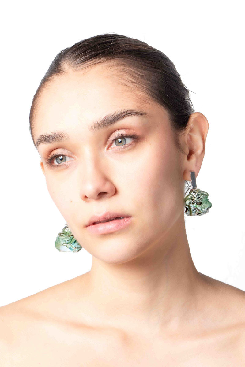 Salvárea Soplo M green earrings featuring a modern design, shown on a model with the earrings prominently displayed.