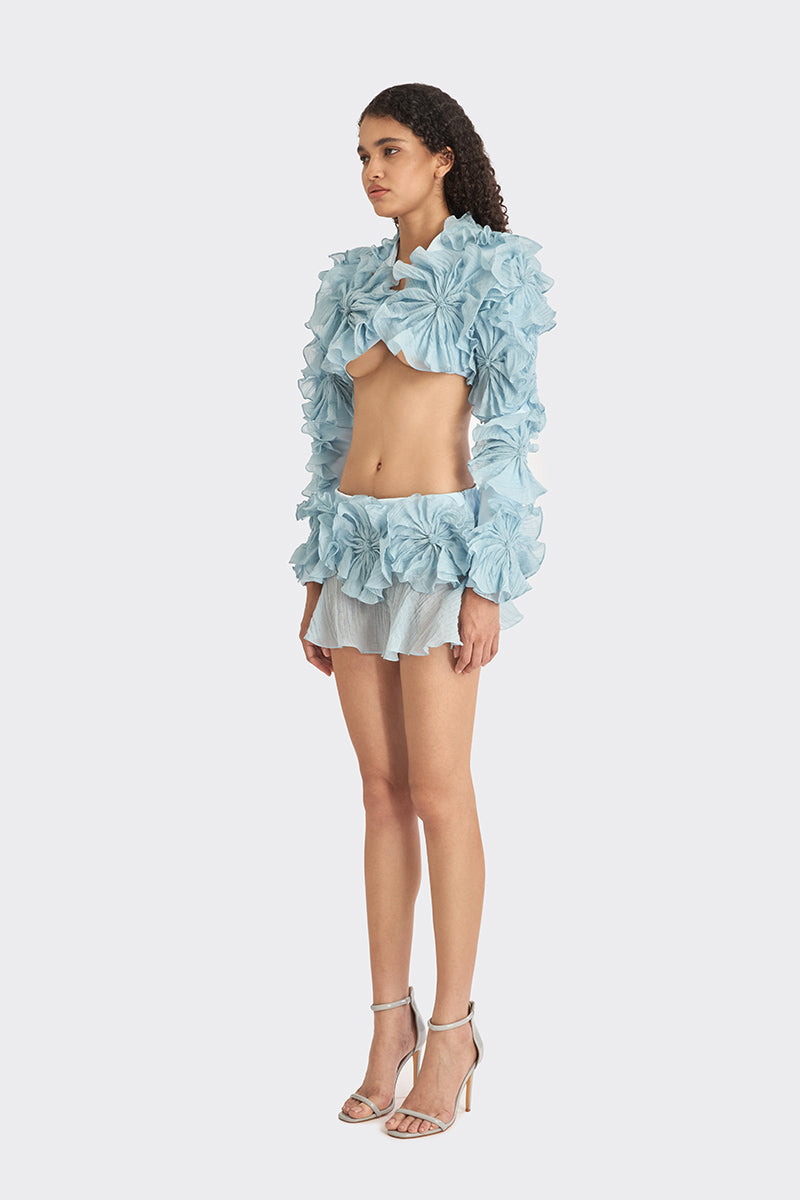 Blue lotus leaf bolero jacket by Stolen Stores, featuring a spiral leaf design, displayed on a hanger against a plain background.