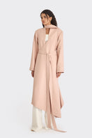 Dusty pink spiral wrap coat by Stolen Stores displayed on a hanger, showcasing its unique wrap design and soft fabric.