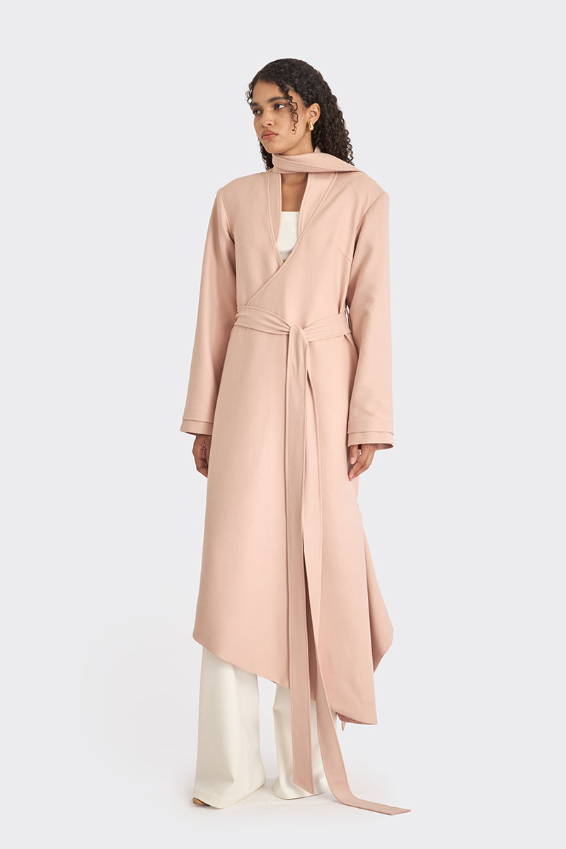 Dusty pink spiral wrap coat by Stolen Stores displayed on a hanger, showcasing its unique wrap design and soft fabric.
