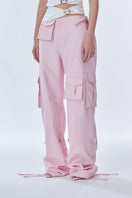 Pink cargo pants by Stolen Stores with multiple pockets and relaxed fit, shown on a model against a neutral background.