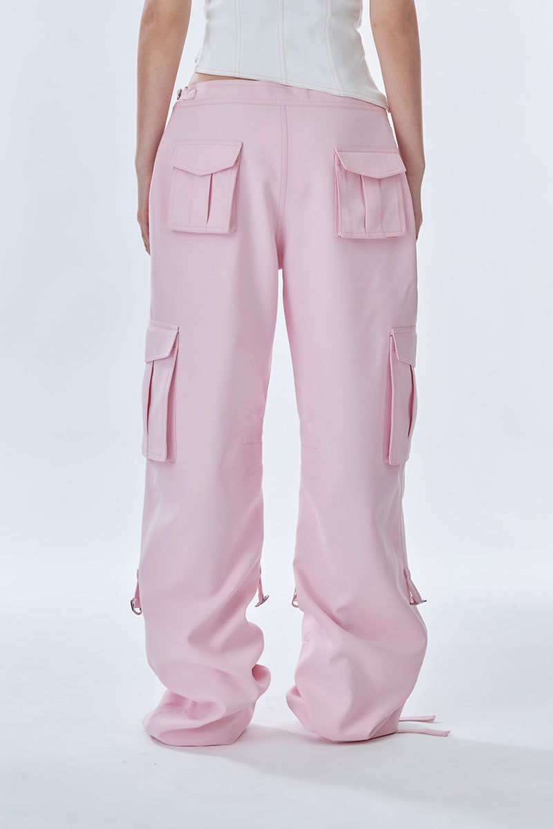 Pink cargo pants by Stolen Stores featuring multiple pockets and a relaxed fit, displayed on a hanger.
