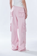 Pink cargo pants by Stolen Stores, featuring multiple pockets and a relaxed fit, shown on a model.