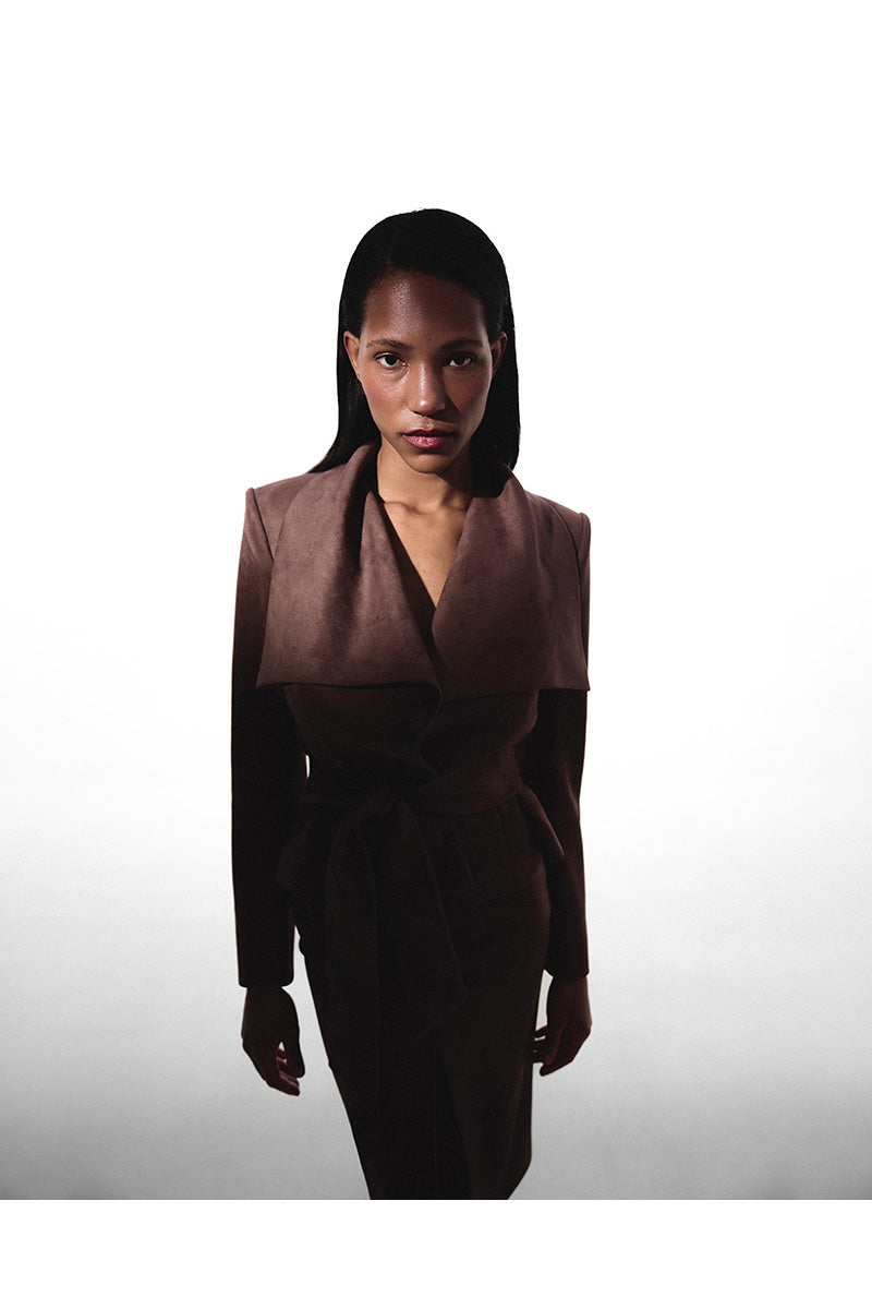 Brown suede mini trench jacket by Kris Marán, shown with classic collar and button details on a neutral background.
