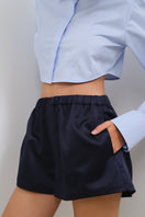 TAGG cropped poplin shirt with shoulder pads, featuring a fitted design and classic collar, shown on a model.