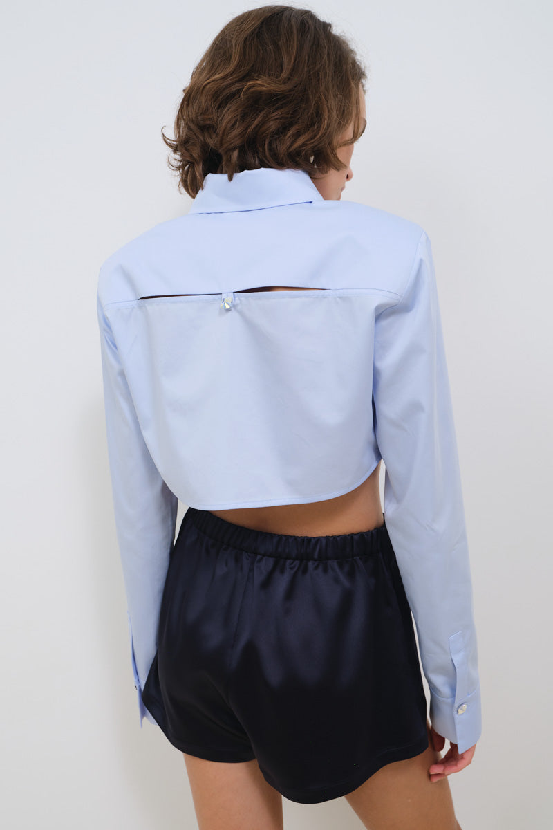 Light blue cropped poplin shirt with shoulder pads from TAGG, featuring a fitted design and classic collar.