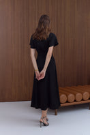 Black structured Tori midi dress by UNDRESS, showcasing a fitted silhouette and elegant design on a model.