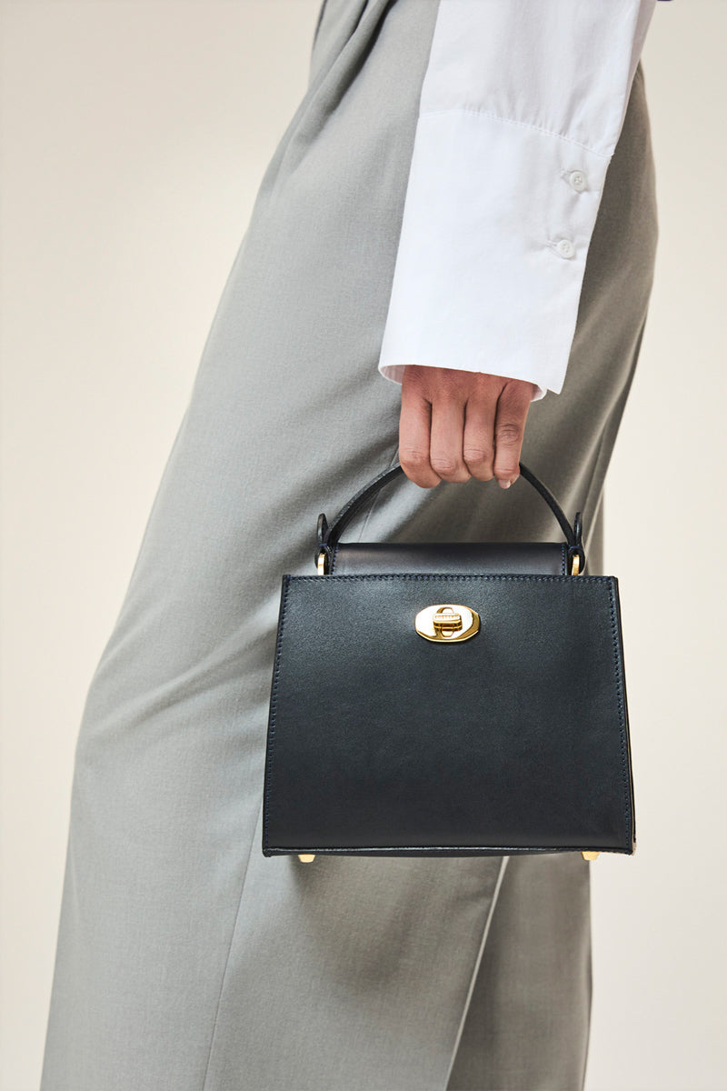 Navy TUSTING Clara top handle bag with structured design and dual top handles, stylish and versatile for everyday use.