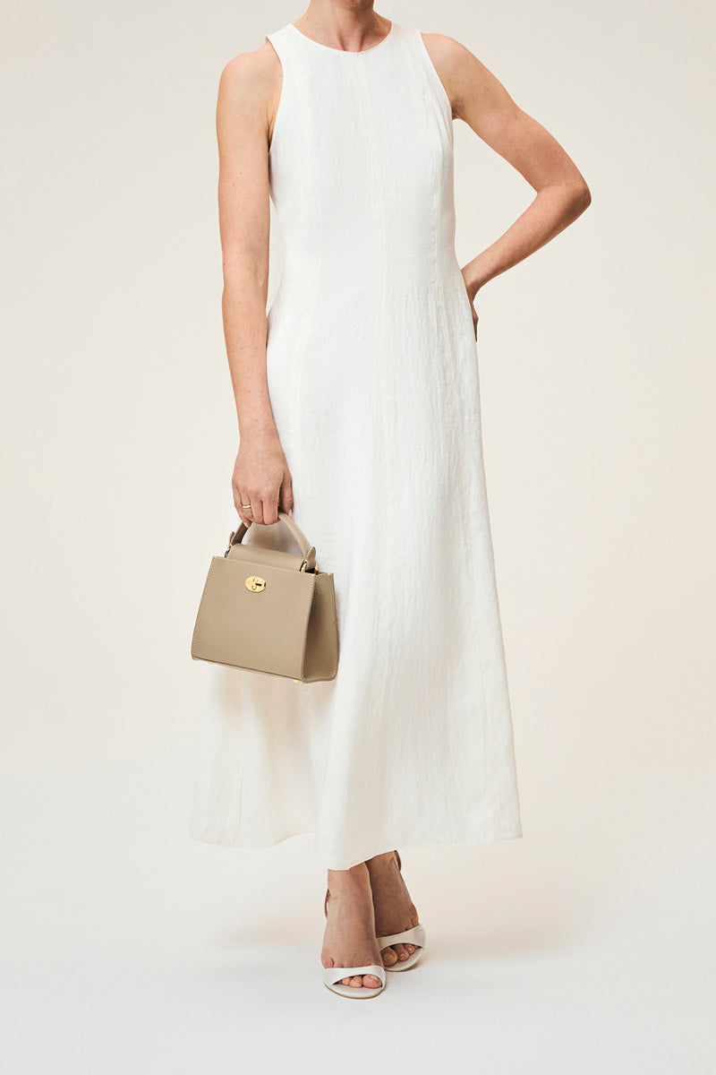 Taupe TUSTING Clara top handle bag with sleek design and gold accents, featuring a structured silhouette and elegant leather finish.