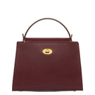 TUSTING Clara Grande oxblood top handle bag with structured design and gold-tone hardware, featuring a sleek, polished appearance.