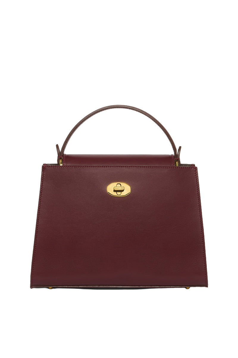 TUSTING Clara Grande top handle bag in oxblood leather with structured design and dual top handles.