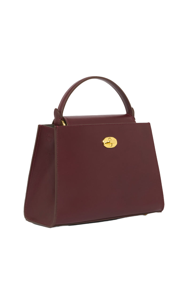 TUSTING Clara Grande Oxblood top handle bag with structured design and sleek leather finish, showcasing its elegant style.